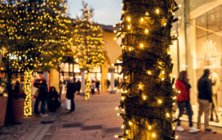 Warm white curtain lights wrapped around outdoor trees outside the shopping centre as a part of their Christmas display.