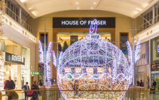 A 3D bauble motif in bright white and warm white lights displayed in the middle of a shopping centre.