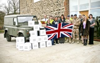 Fizzco staff members stood outside Fizzco, holding a union jack flag next to boxes of products.