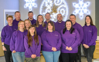 A whole team photo of Fizzco staff members wearing Fizzco's purple uniform in the head office.