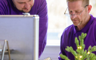 Two Fizzco employees in Fizzco's head office, working together at a desk.