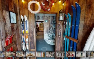 A still image from Fizzco's online Christmas showroom tour, showing the entrance of the showroom with skis attached to the wooden wall.